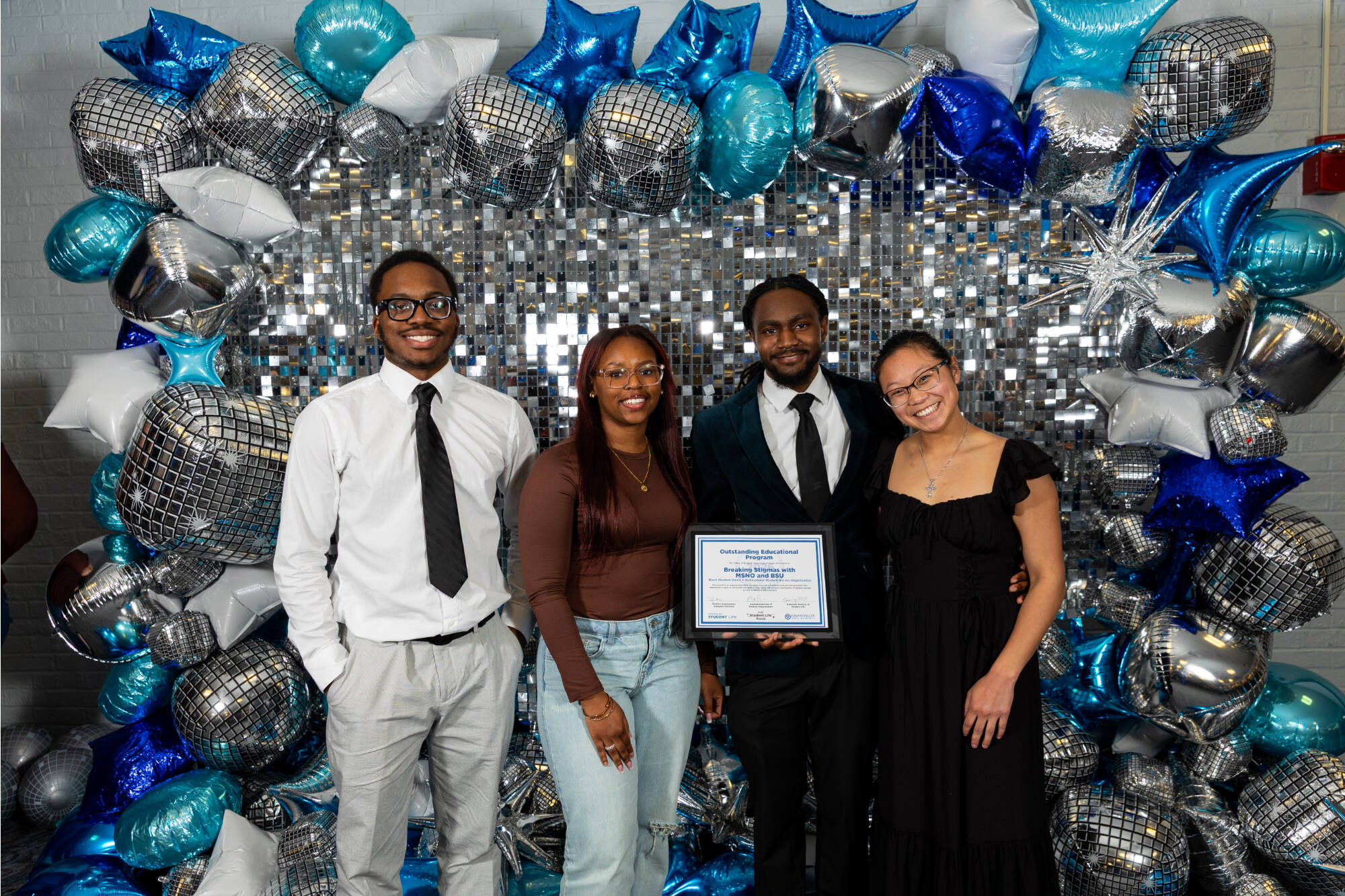 Four individuals holding an award certificate